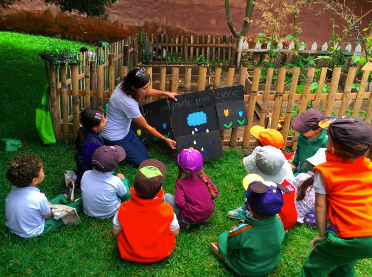 Daniela enseña a un grupo de niños cómo crecen las plantas en un huerto