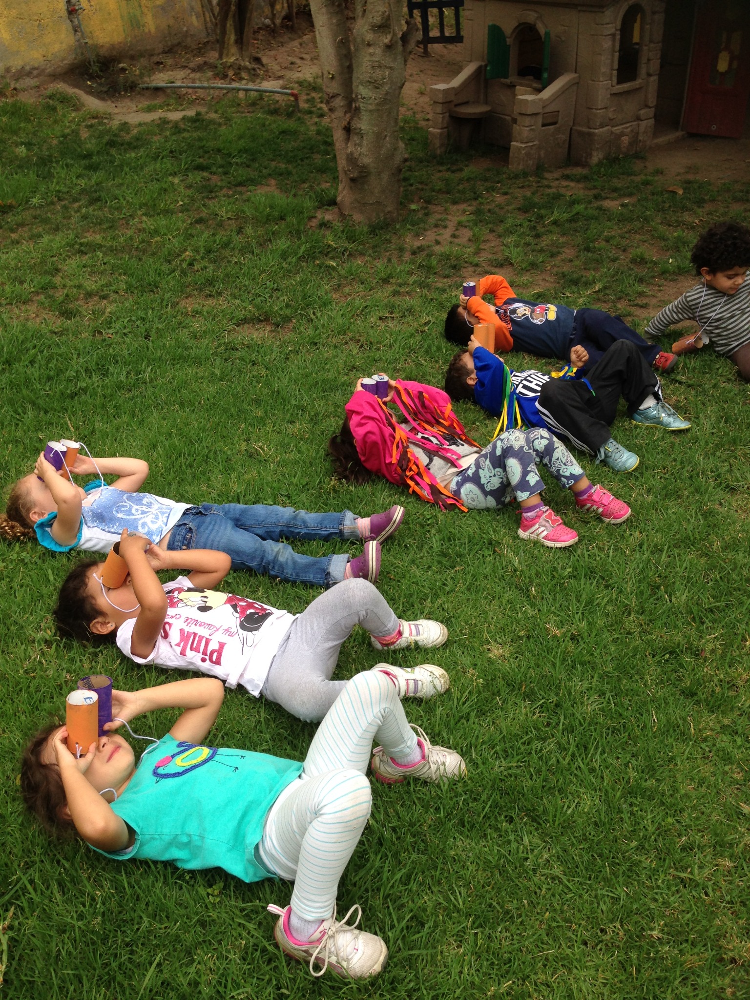 Niños observan aves con visores de cartón sobre el césped
