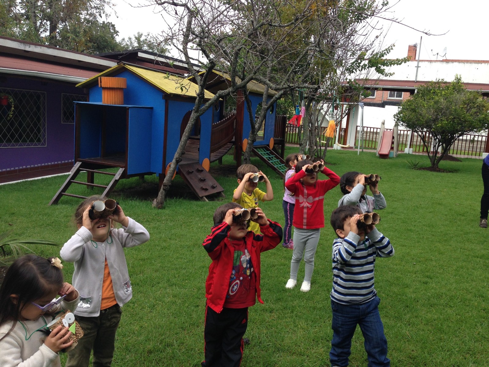 Niños observan aves con visores de cartón sobre el césped